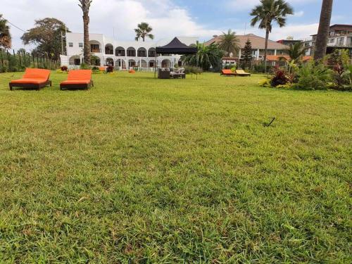 dwie pomarańczowe ławki siedzące na polu trawy w obiekcie Harmony Resort Boutique Hotel w mieście Bandżul