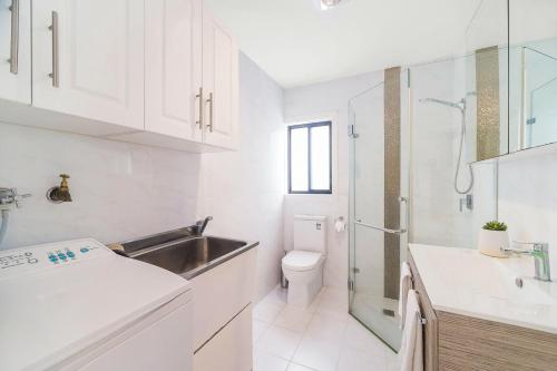Baño blanco con lavabo y aseo en 3 Bedrooms Holiday Home Near Sydney Airport, en Sídney