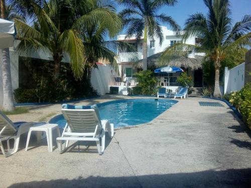 una piscina con tumbonas y palmeras en Casa Marina Antonella, en Pie de la Cuesta