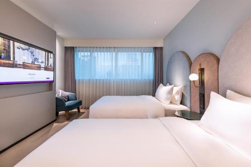 a hotel room with two beds and a flat screen tv at Mercure Fuzhou Downtown in Fuzhou