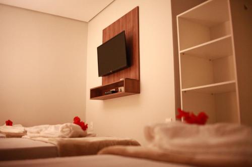 a room with two beds and a television on a wall at Pousada Aconchego Noronha in Fernando de Noronha