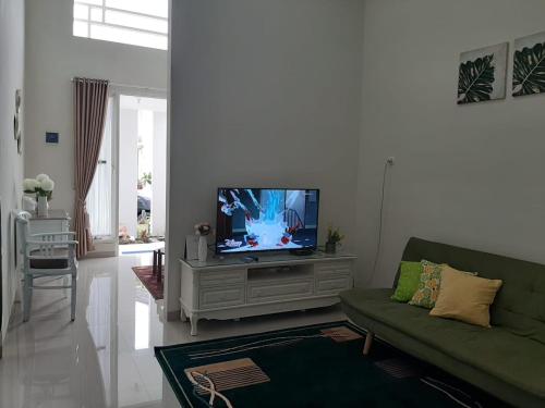 ein Wohnzimmer mit einem grünen Sofa und einem Flachbildfernseher in der Unterkunft Villa Blossom Kayana Regency E7 in Batu