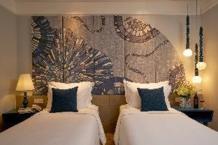 a bedroom with two beds and a mural on the wall at Sofiana My Khe Hotel & Spa- Rooftop Pool Bar in Danang