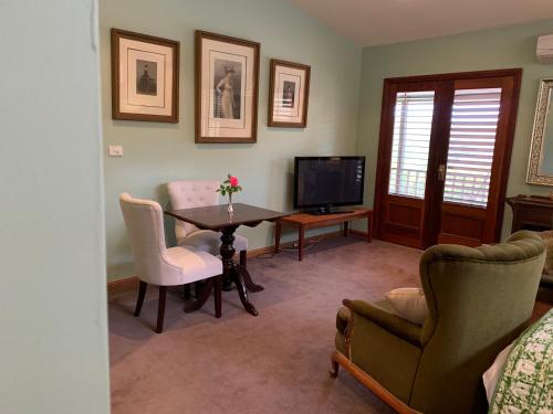 a living room with a table and chairs and a television at Stephanie’s Country Cottages in Drummond