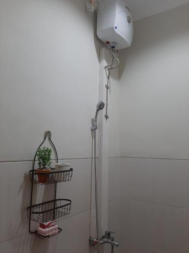 a shower in a bathroom with a plant on a shelf at Villa Blossom Kayana Regency E7 in Batu