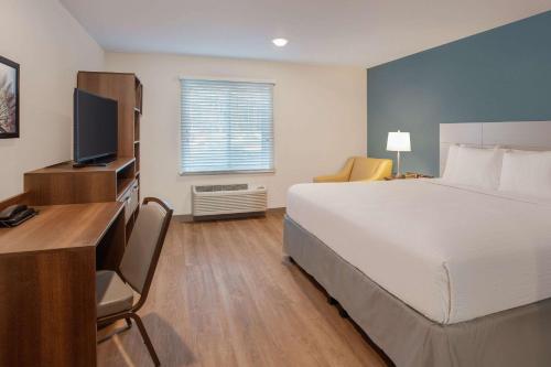 a bedroom with a bed and a desk with a television at Wood Spring Suites Washington DC East Arena Drive in Hyattsville