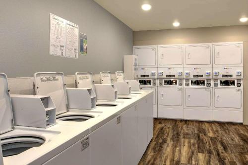 a laundry room with white washing machines and cabinets at WoodSpring Suites Baltimore White Marsh - Nottingham in White Marsh