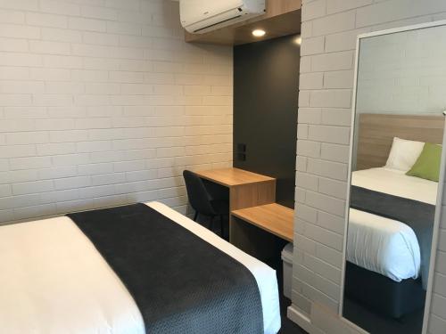 a small room with two beds and a desk at Frewville Motor Inn in Adelaide