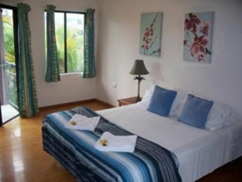 a bedroom with a large bed with blue pillows at Bohemia Resort Cairns in Cairns