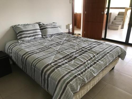 a bed with a striped blanket and pillows in a bedroom at The Heights in Montañita in Montañita