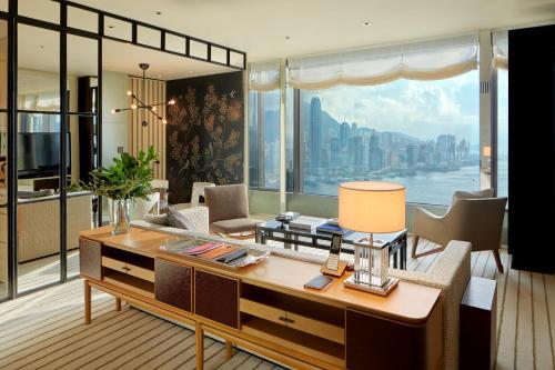 a living room with a desk and a large window at Rosewood Hong Kong in Hong Kong