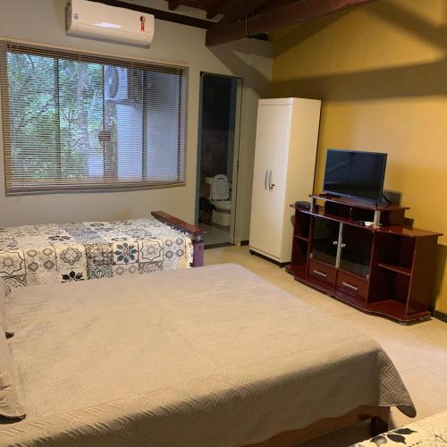 a bedroom with two beds and a flat screen tv at Chalés da Zelma in Capitólio