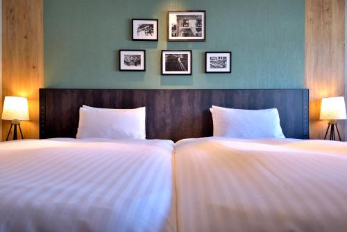 dwa łóżka w sypialni z trzema zdjęciami na ścianie w obiekcie Kobe Portopia Hotel w mieście Kobe
