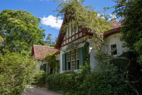 an old white house with green shutters and trees at Pousada da Alcobaça in Itaipava