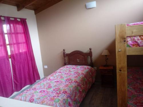 a bedroom with a bed with a pink comforter at Las casitas de Mar in Mar de Ajó