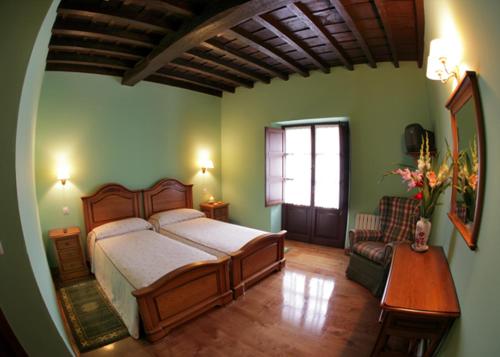 um quarto com uma cama, uma cadeira e uma janela em Posada de Fidel em Puentenansa