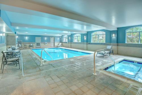 a large swimming pool with chairs and a table in a building at Holiday Inn Express Woodbridge, an IHG Hotel in Avenel