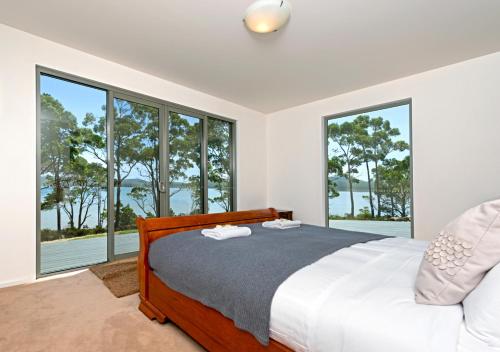 a bedroom with a bed and large windows at Cloudy Bay Lagoon Estate in South Bruny