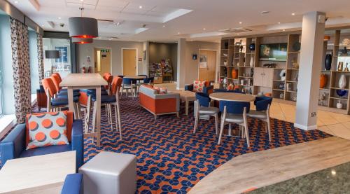 a restaurant with tables and chairs in a cafeteria at Holiday Inn Express Dunfermline, an IHG Hotel in Dunfermline