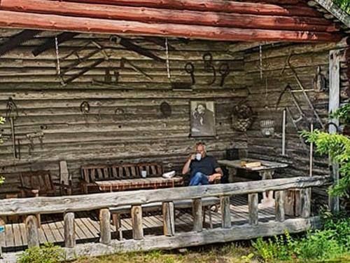 Ein Mann, der vor einem Blockhaus sitzt. in der Unterkunft 8 person holiday home in STMARK in Östmark