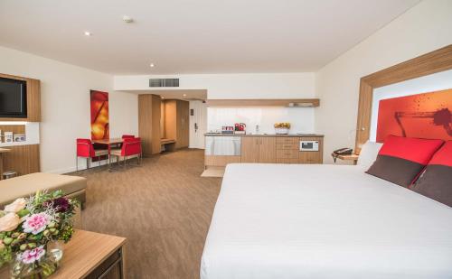 ルーティ・ヒルにあるNovotel Sydney West HQの大きなベッドとキッチンが備わるホテルルームです。