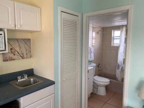 Baño blanco con aseo y lavamanos en Carousel Motel -Redington Shores en Redington Shores