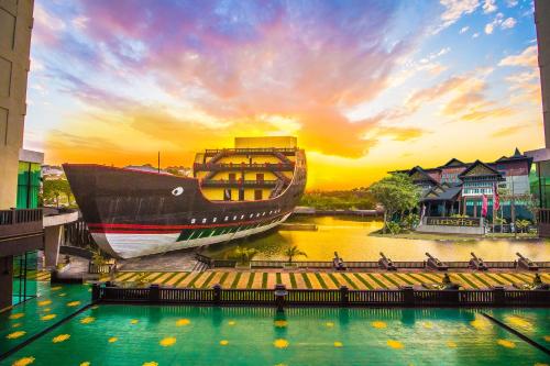 a large boat sitting in the water at sunset at Mudzaffar Hotel in Melaka