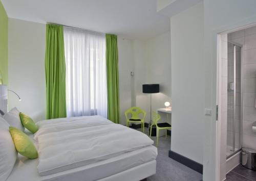 a bedroom with a bed with green curtains and a table at Hotel City Inn Basel in Basel
