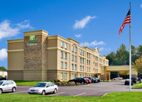 a hotel with cars parked in a parking lot at Holiday Inn Express & Suites West Long Branch - Eatontown by IHG in West Long Branch