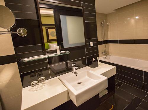 ein Badezimmer mit einem Waschbecken, einem Spiegel und einer Badewanne in der Unterkunft Mudzaffar Hotel in Malakka