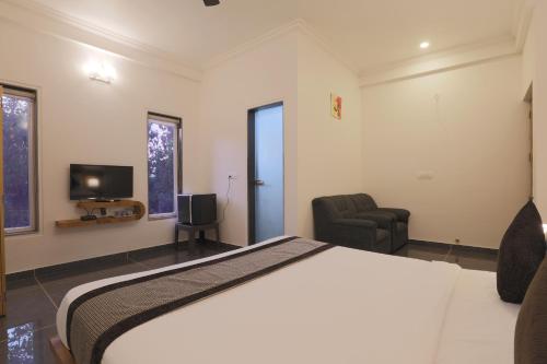 a bedroom with a bed and a chair and a television at Rankk Stays in Arambol