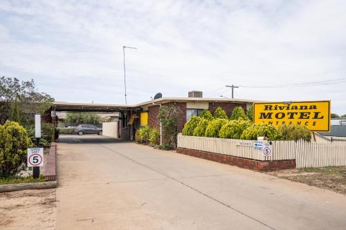 un motel con un cartello giallo sul lato di una strada di Riviana Motel a Deniliquin