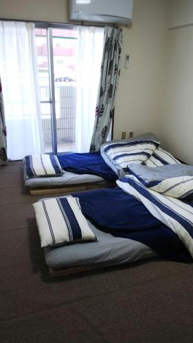 a room with four beds in a room with a window at Cherry Blossom Koseicho in Okayama