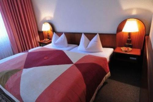 a bedroom with a red and white bed with two lamps at Hotel Luginsland in Schleiz