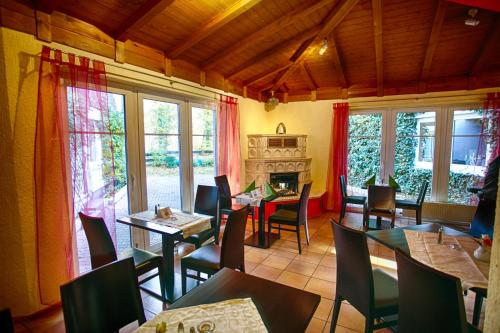 a dining room with tables and chairs and windows at Hotel Rosengarten Leipzig-Naunhof in Naunhof