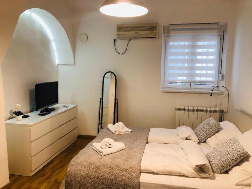 a bedroom with a bed and a dresser and a television at Apartman Tina in Novi Sad