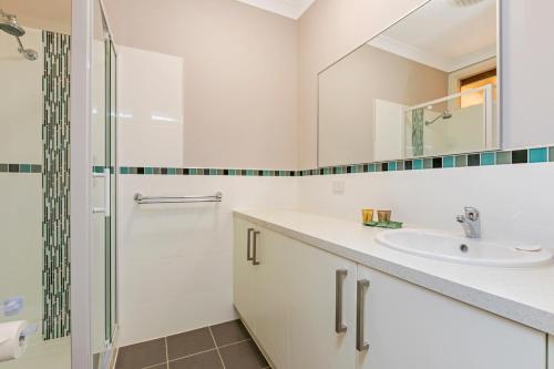 a white bathroom with a shower and a sink at Erldunda Desert Oaks Resort in Erldunda