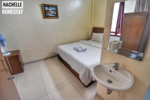 a small bathroom with a bed and a sink at Nachelle Homestay in Berastagi