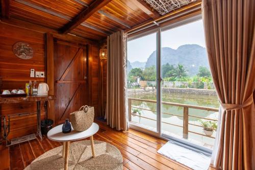 a living room with a large window and a table at Trang An Lamia Bungalow in Ninh Binh