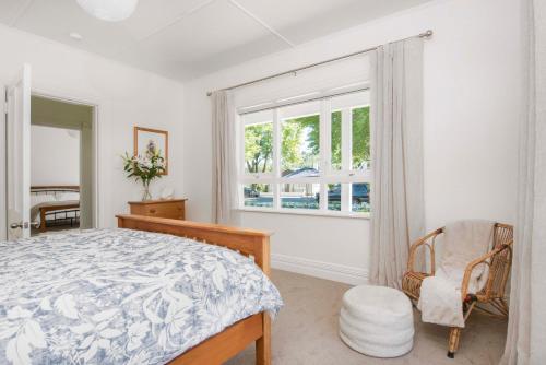 a bedroom with a bed and a chair and a window at Villa Maitai in Nelson