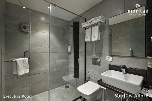 a bathroom with a sink and a toilet and a mirror at Meritas Adore Resort in Lonavala