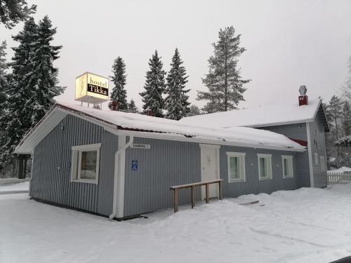 a building with a sign on top of it in the snow at Hostel Tikka in Rovaniemi