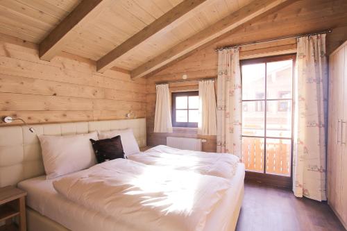 una cama grande en una habitación con ventana en Alpenchalets Flachauer Gutshof, en Flachau