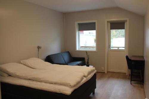 Una habitación con una cama y una silla y ventanas. en Utvika Camping, en Nes