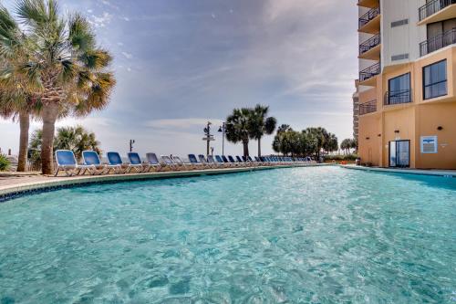 a swimming pool with chairs and palm trees at Ocean-Front Condos at Patricia Grand in Myrtle Beach