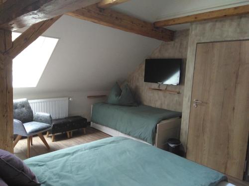 1 dormitorio con 2 camas, TV y silla en B&B Landhof Schober en Weissbriach