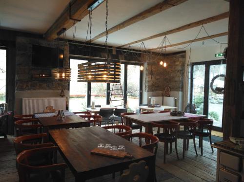 un restaurant avec des tables et des chaises en bois ainsi que des fenêtres dans l'établissement B&B Landhof Schober, à Weißbriach