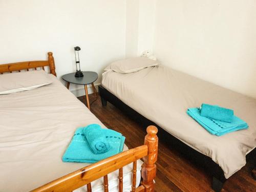 - 2 lits dans une chambre avec des serviettes bleues dans l'établissement chez clion, à Lorigné