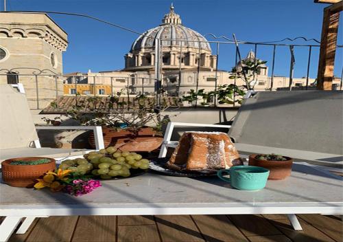 a table with a cake and fruit on a balcony at La CasUPOLA Saint Peter's Quiet Room in Rome