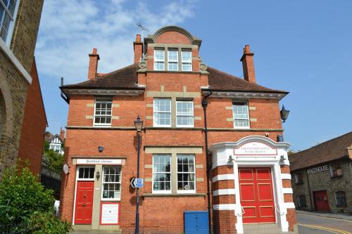 an old brick building with red doors on a street at The Old Post Office Boutique Guesthouse in Hythe